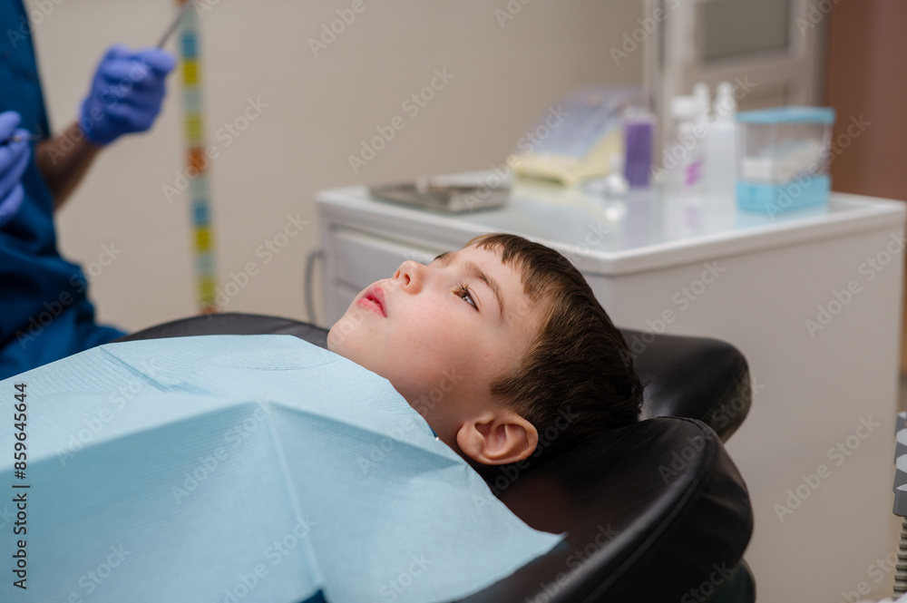 A cute little boy in a dental chair treats his teeth, smiling and happy A cute little boy in a dental chair treats his teeth, smiling and happy