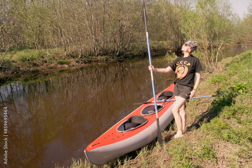 a woman with a paddle in her hands stands next to a kayak a woman with a paddle in her hands stands next to a kayak