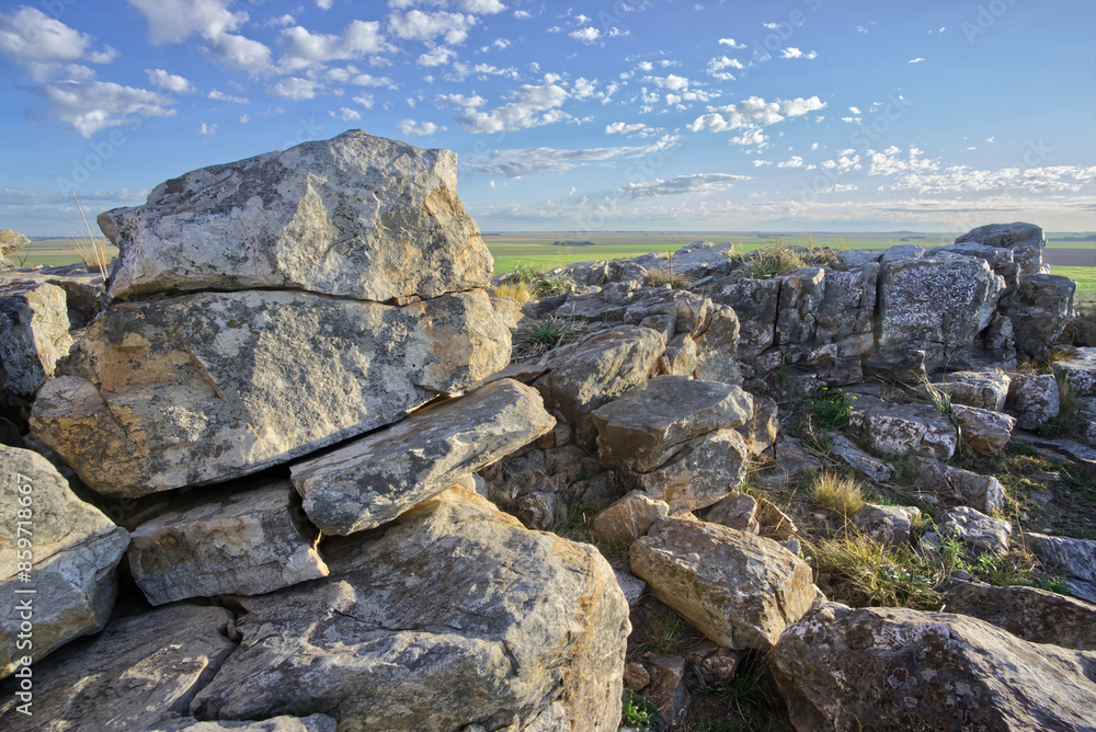 Landscape with ancient rock formations in the foreground and blue sky with clouds Landscape with ancient rock formations in the foreground and blue sky with clouds