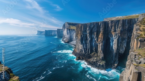 Rugged coastline with dramatic cliffs plunging into the deep blue ocean waves crashing below.