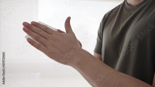 Proper Hand Sanitization Technique Demonstrated with Damp Cloth. A man in a green t-shirt demonstrating the proper hand sanitization technique using a clean damp cloth photo