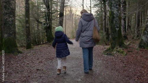 Wallpaper Mural A woman and a child in winter clothes walking hand in hand on a forest path, filmed from the back with no faces visible Torontodigital.ca