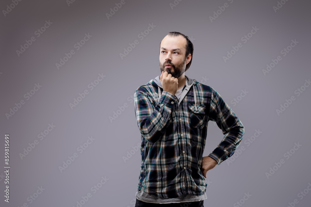Pensive bearded man touching beard thinking looking away on grey Pensive bearded man touching beard thinking looking away on grey