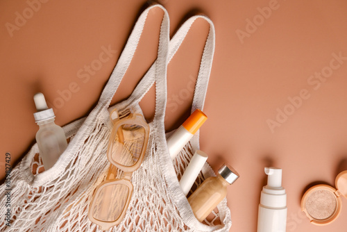 Tote bag containing a variety of skincare or cosmetic products on a light peach background.