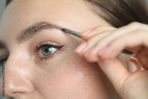 Young woman plucking eyebrow with tweezers, closeup © New Africa