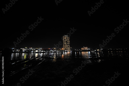 船から遠くの街を眺める 夜の海越しに見える街の光、光の反射 photo