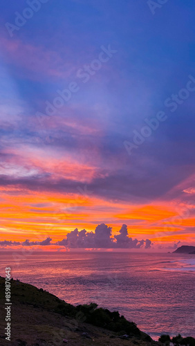 A captivating sunset from Bukit Merese, Lombok, with a brilliant display of purple, pink, and orange hues across the sky and ocean, highlighting the tranquil beauty of the landscape.
 photo