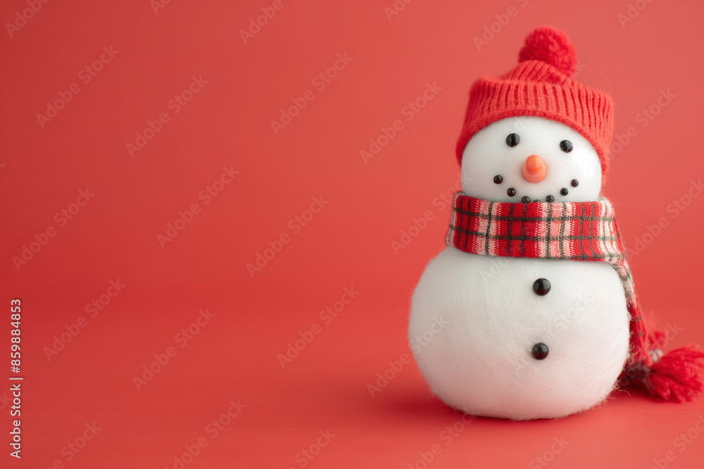 A charming snowman toy wearing a red hat and plaid scarf, set against a bright red background with copy space for mockup A charming snowman toy wearing a red hat and plaid scarf, set against a bright red background with copy space for mockup