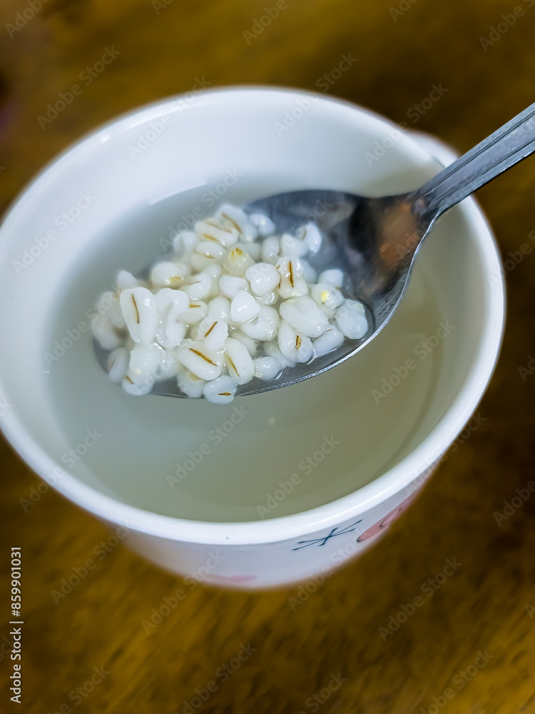 A glass of barley water with a spoon isolated on wooden background. Top view. Barley is good for health. A glass of barley water with a spoon isolated on wooden background. Top view. Barley is good for health.