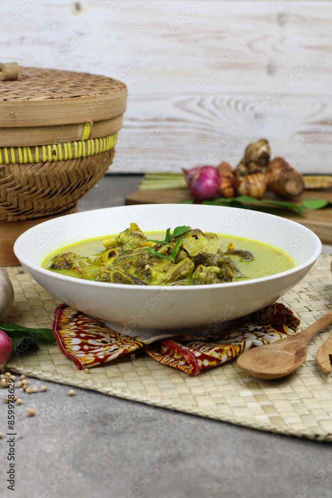 Gulai kambing or Indonesian traditional lamb curry, popular Indonesian food special in hari raya made from lamb meat, spices, and coconut milk. grey rustic background. Gulai kambing or Indonesian traditional lamb curry, popular Indonesian food special in hari raya made from lamb meat, spices, and coconut milk. grey rustic background.