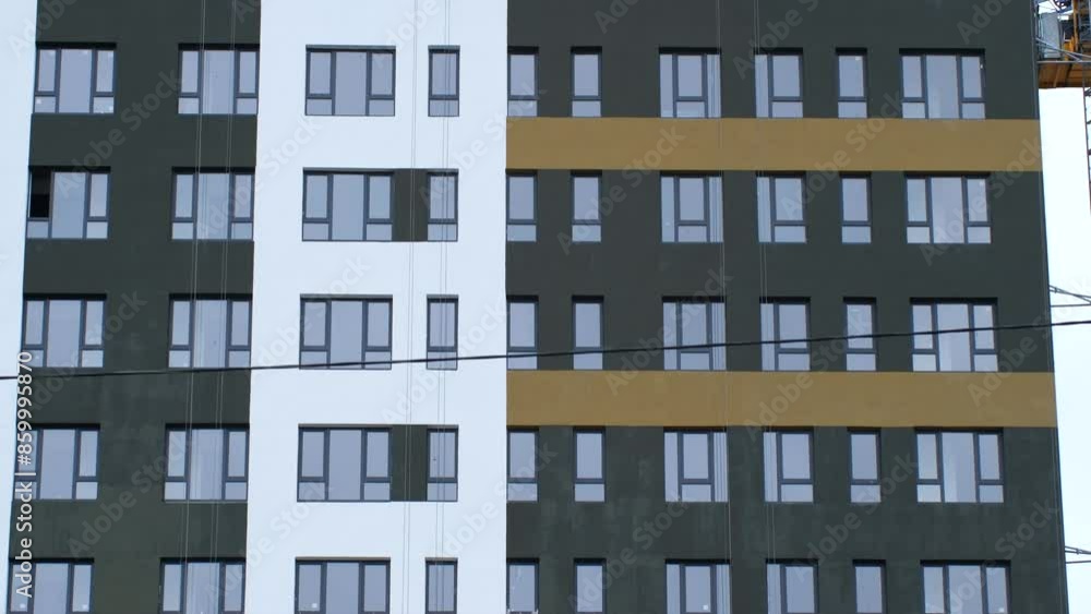 Workers securely stands on high lift near high-rise building. Employees add final touches to ultra-modern facade of newly constructed high-rise Workers securely stands on high lift near high-rise building. Employees add final touches to ultra-modern facade of newly constructed high-rise