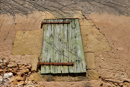 Photography Ancient shabby weatherworn shutter with rusty wrought iron hinges in a French me