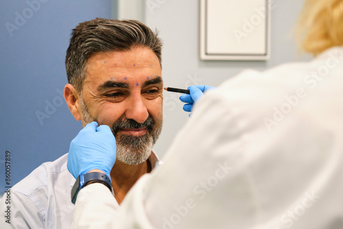 A man is getting ready to get Botox for crow's feet or laugh lines wrinkles by a aesthetic doctor in a clinic.