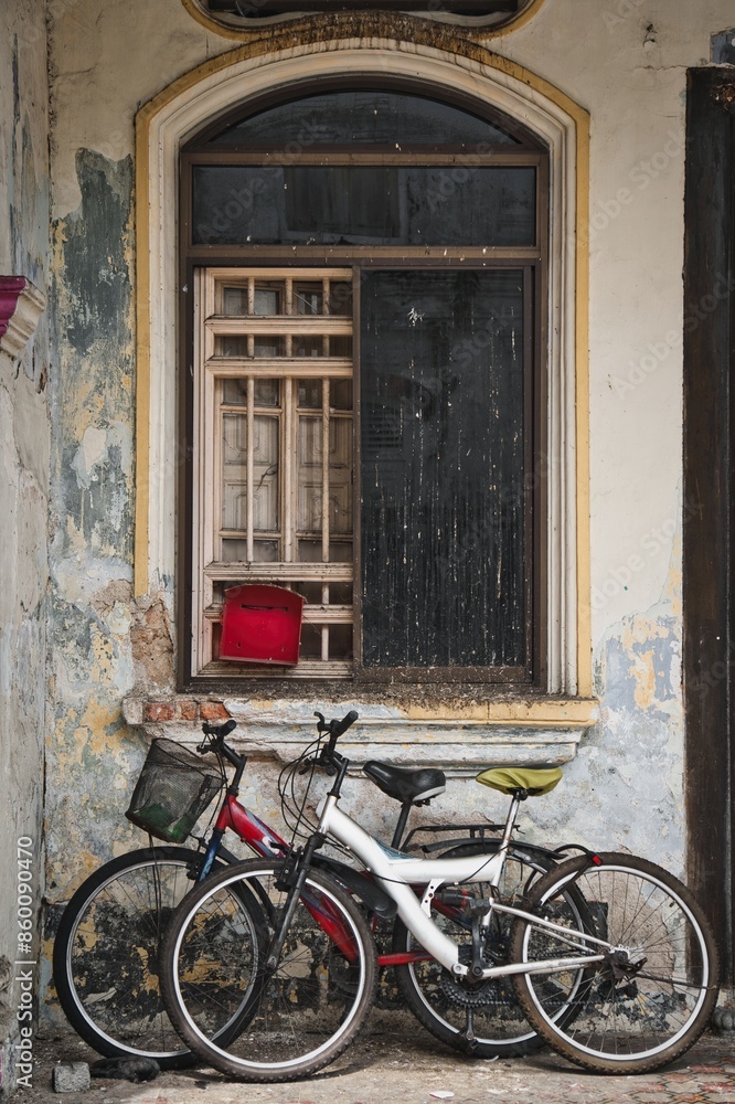 Old rusty bicycles parked in front of window of abandoned house. Old rusty bicycles parked in front of window of abandoned house.