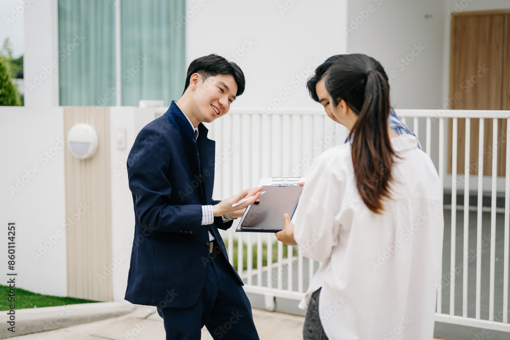 Asian man Real estate broker agent showing a house detail in her file to the young Asian couple lover looking and interest to buy it. Asian man Real estate broker agent showing a house detail in her file to the young Asian couple lover looking and interest to buy it.