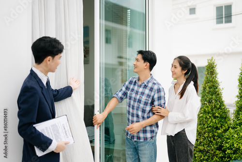 Asian man Real estate broker agent showing a house detail in her file to the young Asian couple lover looking and interest to buy it.