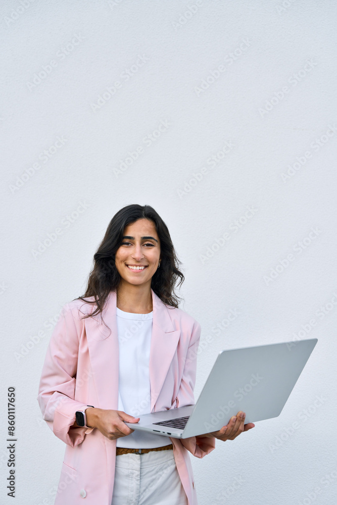 Vertical portrait of young middle eastern Israel businesswoman using laptop pc online application for work isolated on white wall. Smiling happy indian, arabic woman in business suit holding computer Vertical portrait of young middle eastern Israel businesswoman using laptop pc online application for work isolated on white wall. Smiling happy indian, arabic woman in business suit holding computer