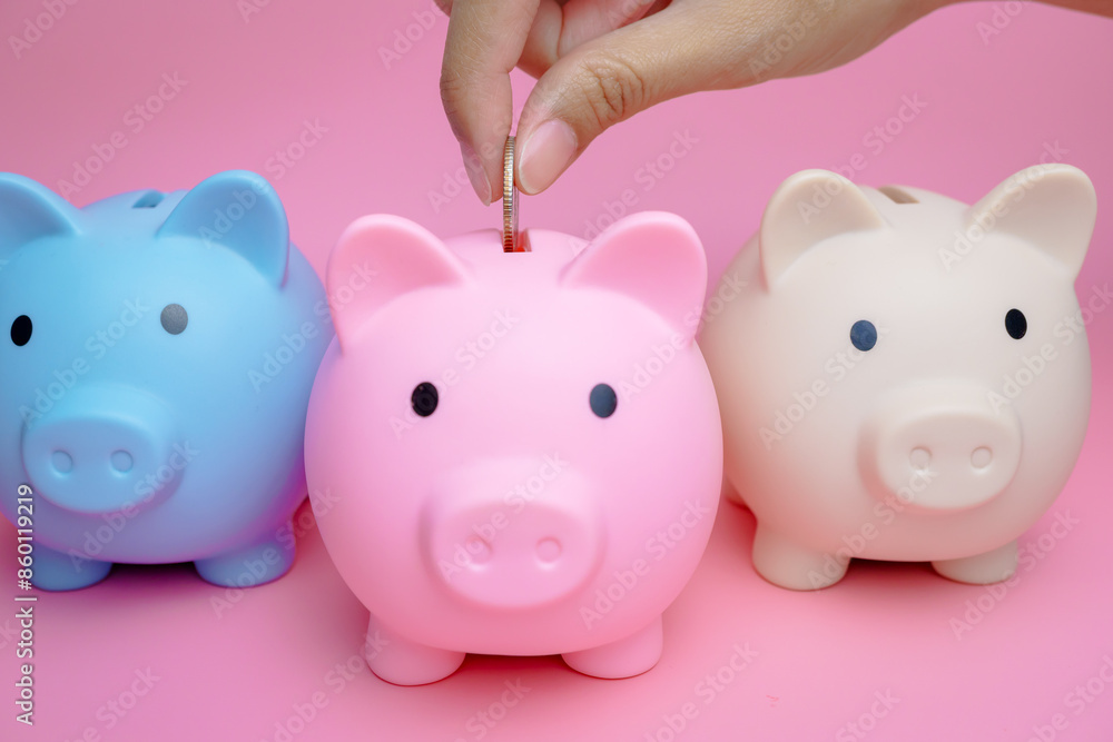 A woman's hand is putting coins into a piggy bank. A woman's hand is putting coins into a piggy bank.