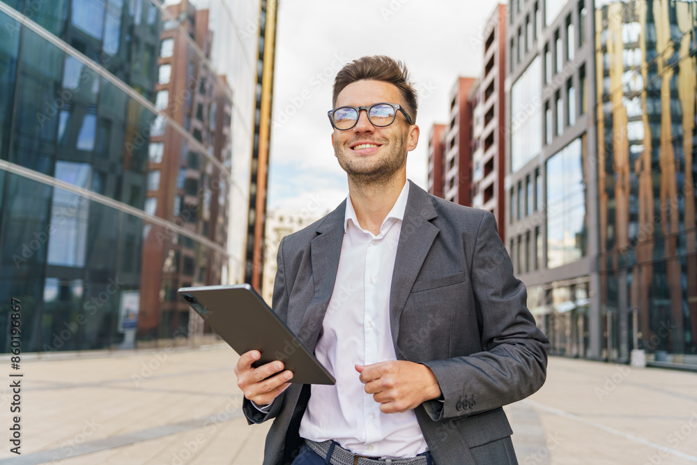 A cheerful businessman in a suit holds a tablet, standing confidently amid modern urban buildings. A cheerful businessman in a suit holds a tablet, standing confidently amid modern urban buildings.