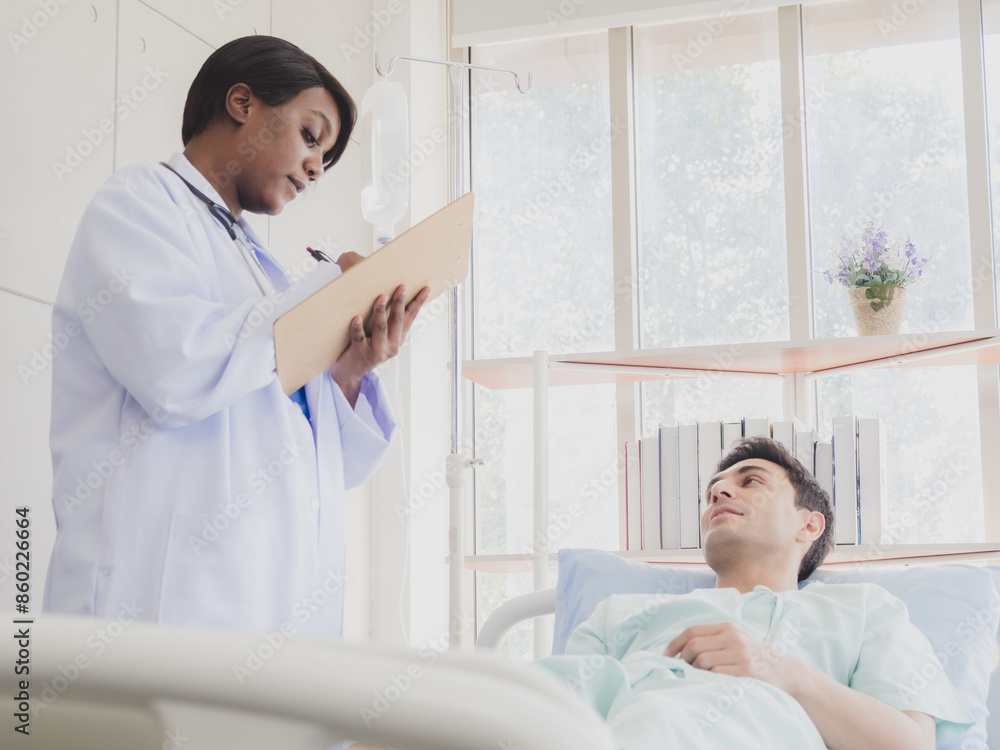 Portrait patient caucasian man lying bed with woman doctor African-American standing carer physical therapist two people talk helping support and check treat sick person inside hospital room service. Portrait patient caucasian man lying bed with woman doctor African-American standing carer physical therapist two people talk helping support and check treat sick person inside hospital room service.