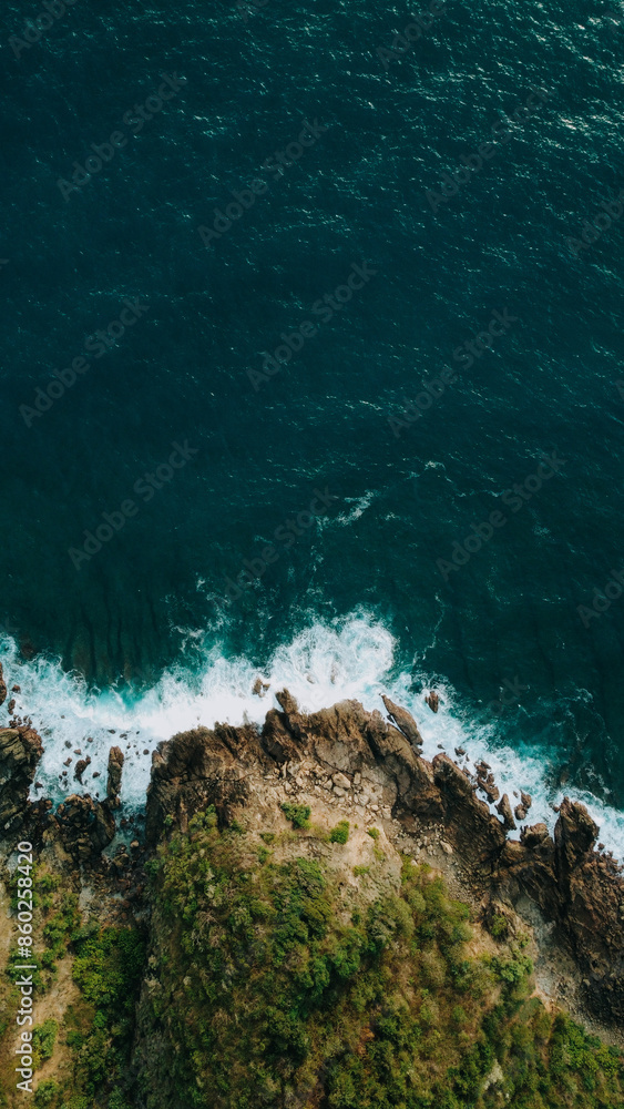 Aerial view of Mawun Beach, Lombok, highlighting waves crashing against rocky cliffs and lush greenery, showcasing the rugged natural beauty of this secluded tropical paradise.
Aerial view of Mawun Beach, Lombok, highlighting waves crashing against rocky cliffs and lush greenery, showcasing the rugged natural beauty of this secluded tropical paradise.