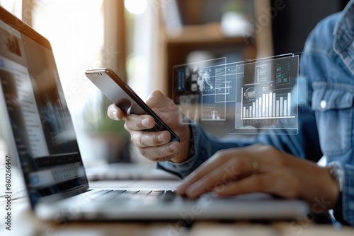A person uses a smartphone and laptop, with data visualization appearing on the screen, highlighting the intersection of technology and business