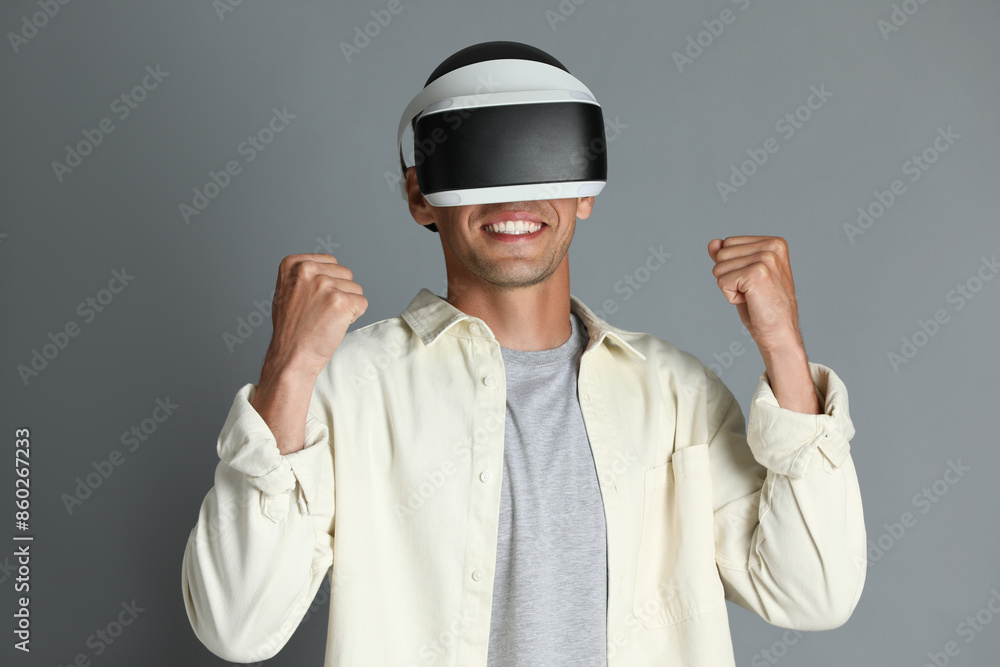 Smiling man using virtual reality headset on gray background Smiling man using virtual reality headset on gray background