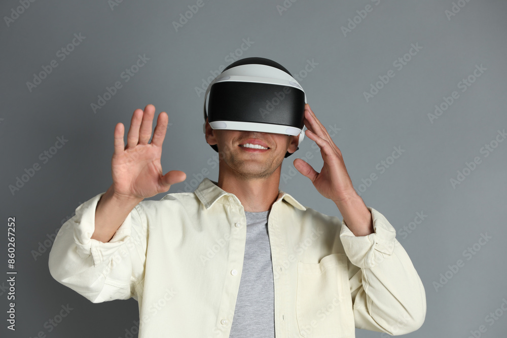 Smiling man using virtual reality headset on gray background Smiling man using virtual reality headset on gray background