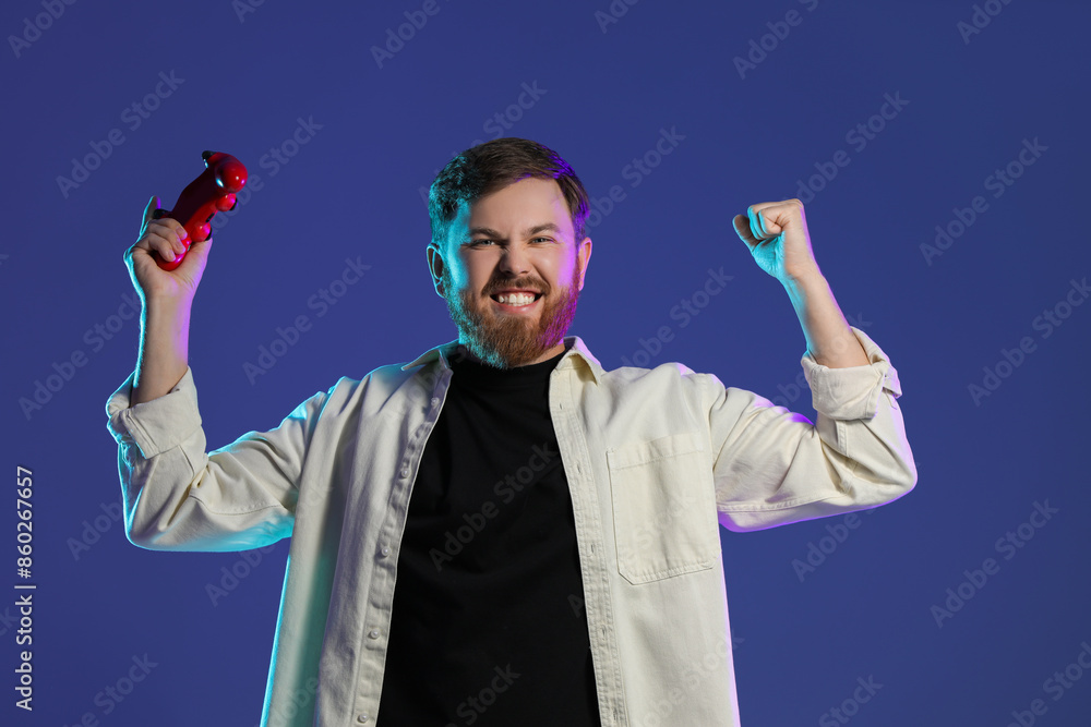 Emotional man with game controller on dark blue background Emotional man with game controller on dark blue background