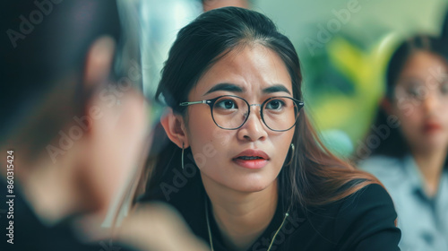 A woman with glasses leans forward, listening intently during a serious conversation, showing her engagement and concern. Free Download A woman with glasses leans forward, listening intently during a serious conversation, showing her engagement and concern. - GFXLoad