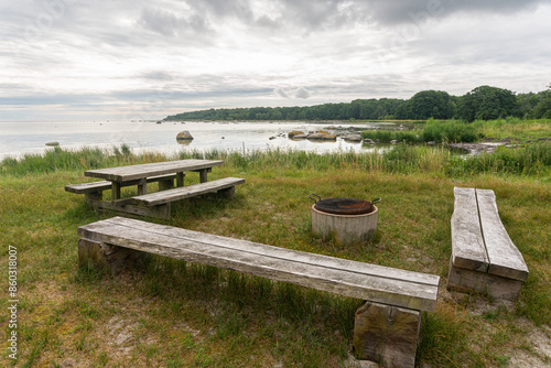 Wooden benches, a table, and a grill by the seaside