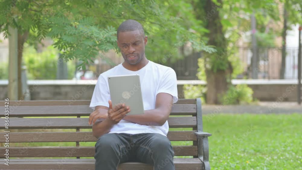 Video Chat via Tablet by African American Man Sitting on Bench in Park Video Chat via Tablet by African American Man Sitting on Bench in Park