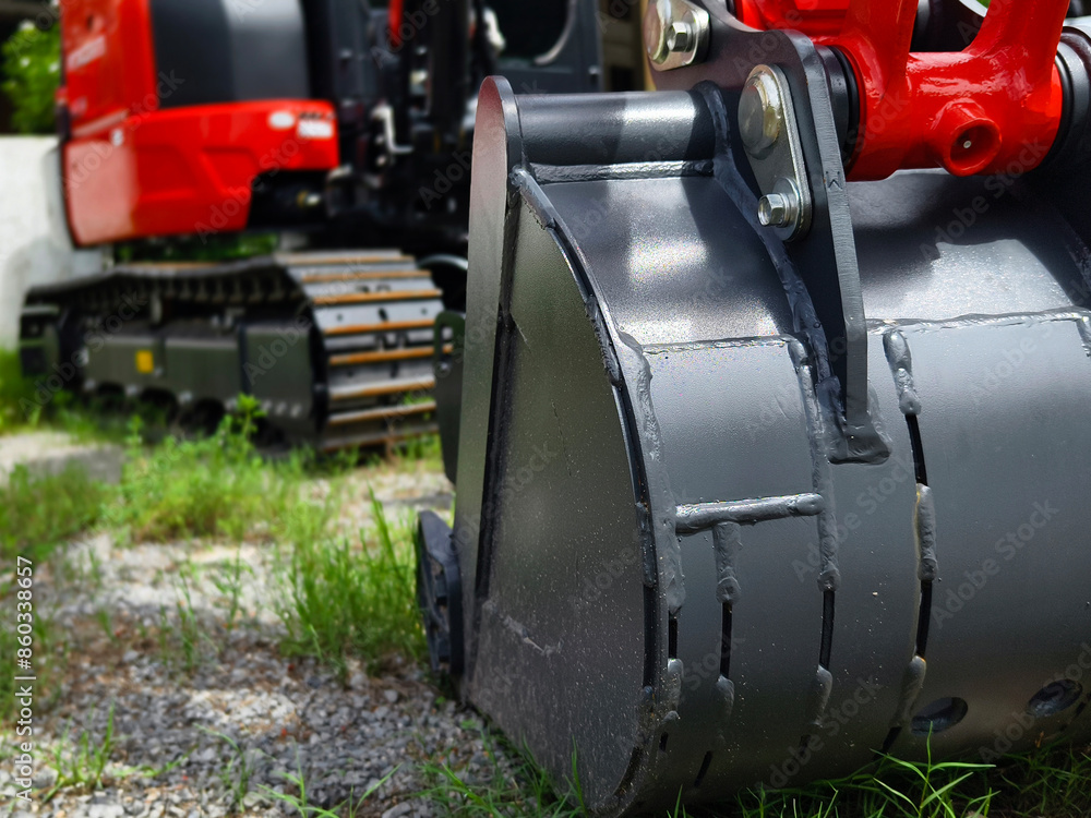 Red large excavators are stationed in a green field in front of a building Red large excavators are stationed in a green field in front of a building