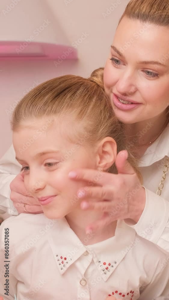 Mom teaches her daughter to use cosmetics in the bright kitchen in the evening. Joint activities between mother and daughter. Vertical video. Mom teaches her daughter to use cosmetics in the bright kitchen in the evening. Joint activities between mother and daughter. Vertical video.