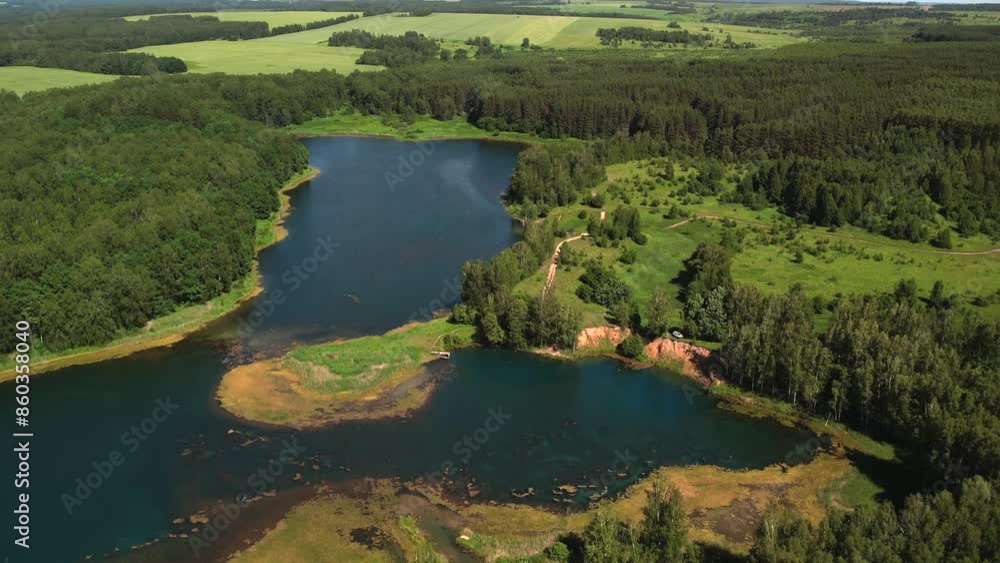 Incredible bird's eye view of the blue lake. Tourists ride SUP boards and set up tents around. Green forest and silence Incredible bird's eye view of the blue lake. Tourists ride SUP boards and set up tents around. Green forest and silence