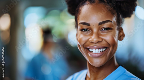 Portrait of a happy nurse in a medical gown in the corridor of a modern hospital. A young hospital employee laughs indoors. Medicine and doctor concept.