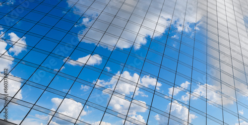 Fototapeta Naklejka Na Ścianę i Meble -  Reflection of a blue sky with white clouds on the glass wall of a skyscraper in the business center of the cityscattered throughout