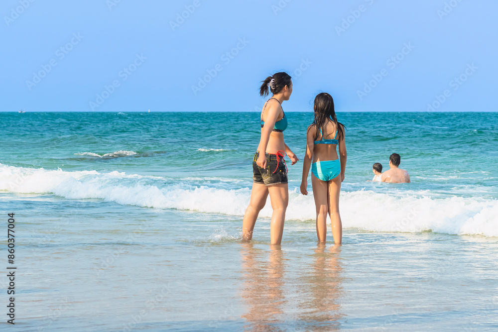 Mother and teenage daughter playing together on tropical beach at daytime. Mom and lovely daughter enjoy and fun outdoor lifestyle on beach. Happy family outdoors vacation. Friendly family Concept. Mother and teenage daughter playing together on tropical beach at daytime. Mom and lovely daughter enjoy and fun outdoor lifestyle on beach. Happy family outdoors vacation. Friendly family Concept.