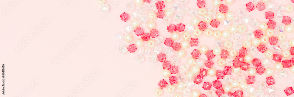 Different acrylic beads scattered on a pink background. Banner with copy space. Different acrylic beads scattered on a pink background. Banner with copy space.
