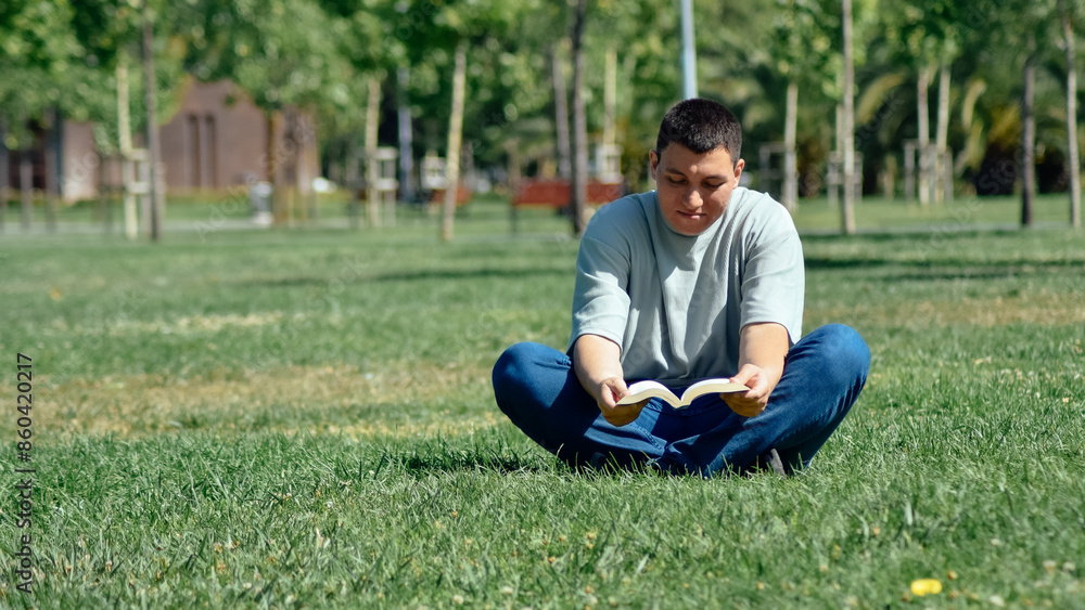 Young man reading a book sitting on the grass Young man reading a book sitting on the grass