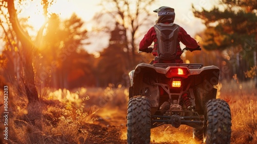 Person riding ATV in forest at sunset
