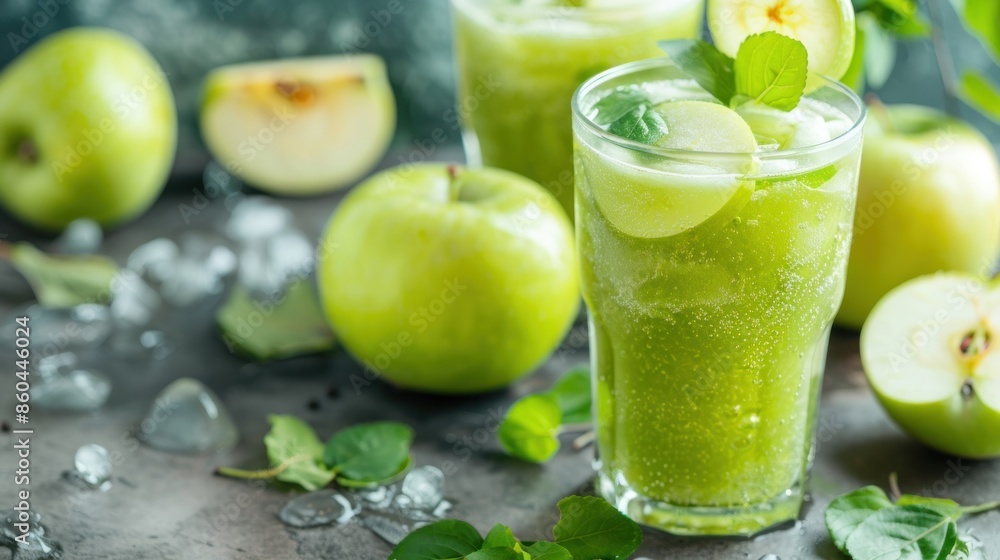 A glass of green apple juice is on a table with several apples A glass of green apple juice is on a table with several apples