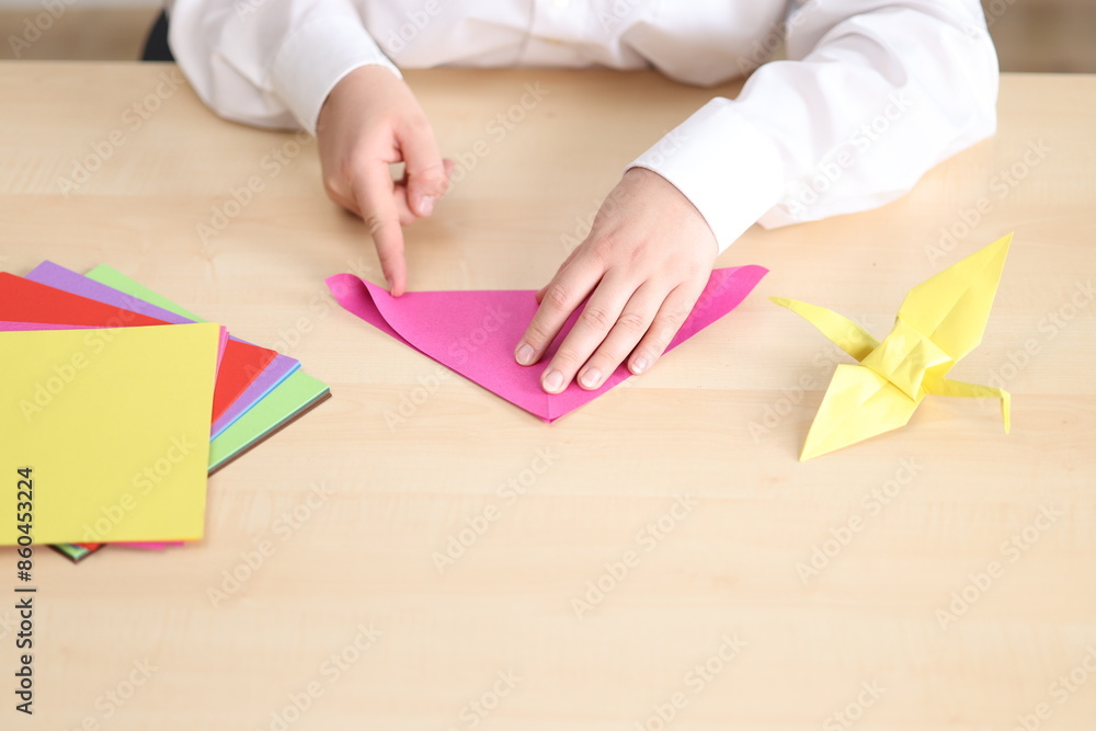 Frau mit weisser Bluse sitzt am Schreibtisch und faltet Papierfiguren und Origami Frau mit weisser Bluse sitzt am Schreibtisch und faltet Papierfiguren und Origami