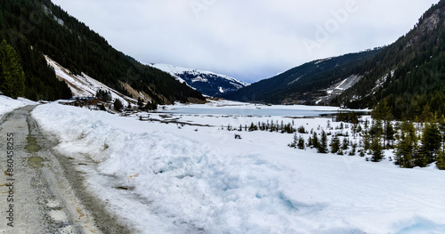 Mountain lake near Königsleiten in Austria. Snowy road and frozen lake in the Alps.