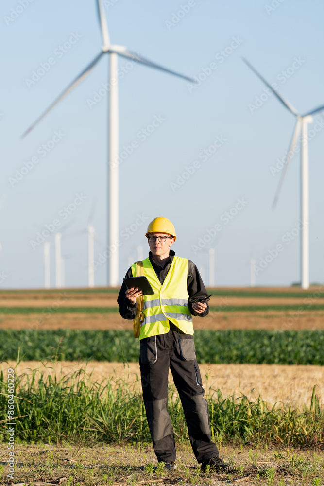 Engineer with digital tablet works on a field of wind turbines Engineer with digital tablet works on a field of wind turbines