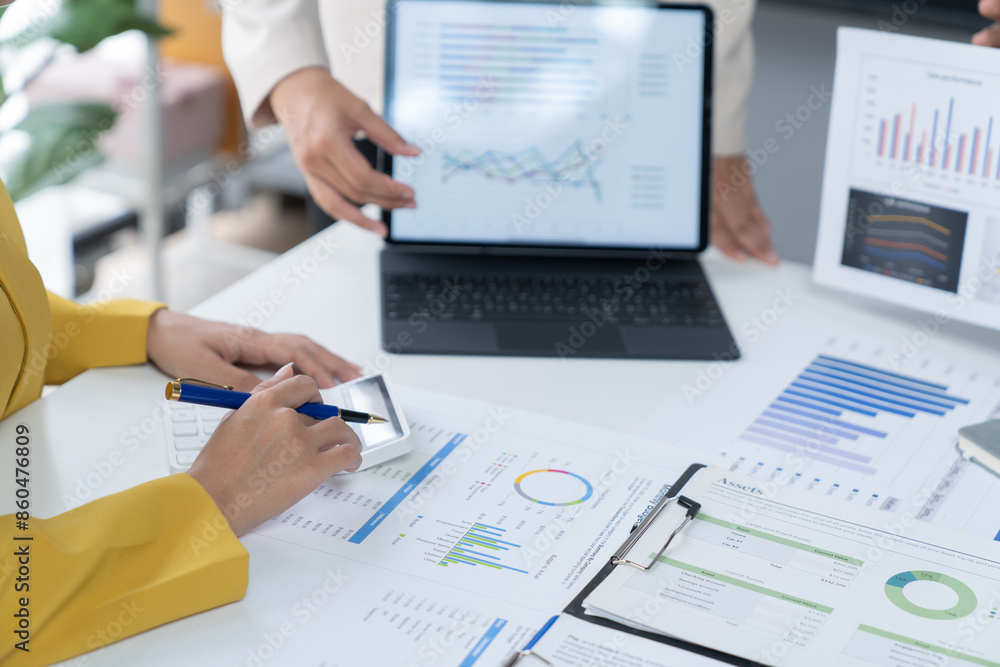 A photograph of a male and female employee's hands as they meet in an office, pens and laptops at the ready as they consult on business matters. A photograph of a male and female employee's hands as they meet in an office, pens and laptops at the ready as they consult on business matters.