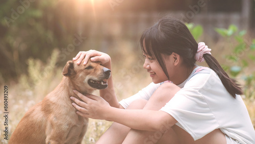 A cute little girl raises a dog with gentleness and friendliness. Concept of showing love and caring for pets. Pet owner and dog smile at each other