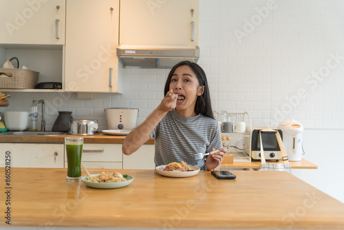 Asian Girl  eating Thai food in kitchen counter Home delivery food feeling happy 