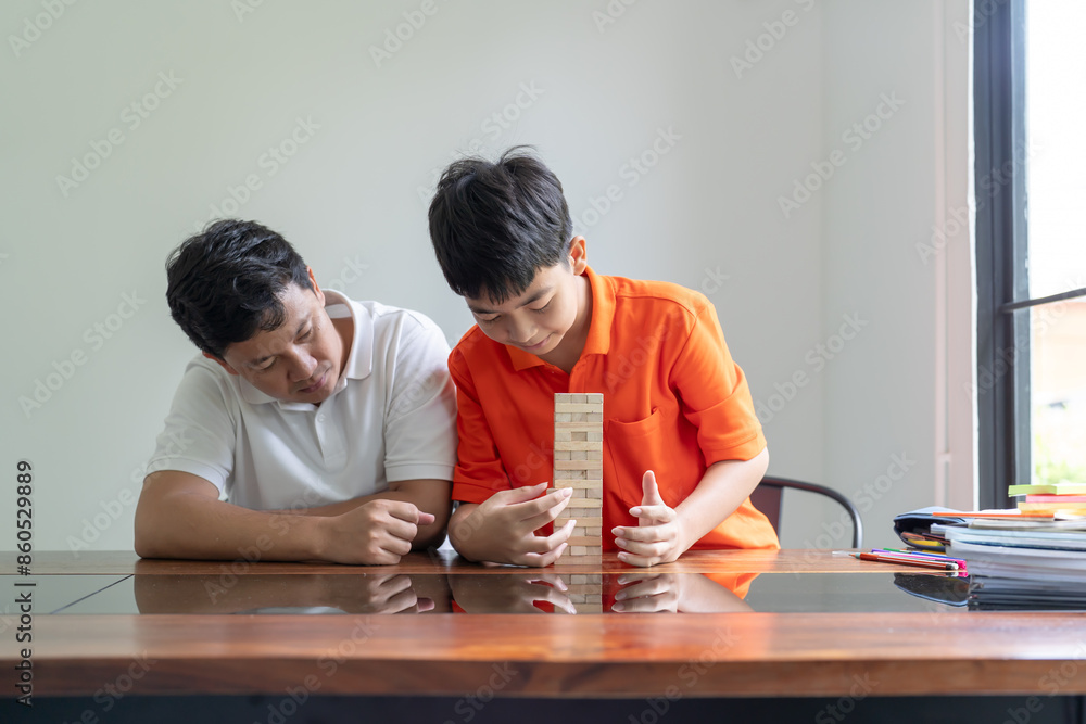 Fototapeta premium Asian father and son playing wood blocks game Carefree kid playing wood blocks game building constructor from blocks with father at home