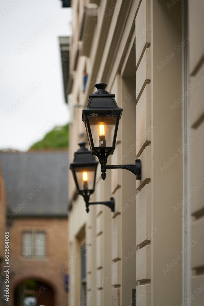 Altstadtgasse mit Laternen an einer Hauswand bei Abenddämmerung in der Altstadt von Brügge in Belgien Altstadtgasse mit Laternen an einer Hauswand bei Abenddämmerung in der Altstadt von Brügge in Belgien